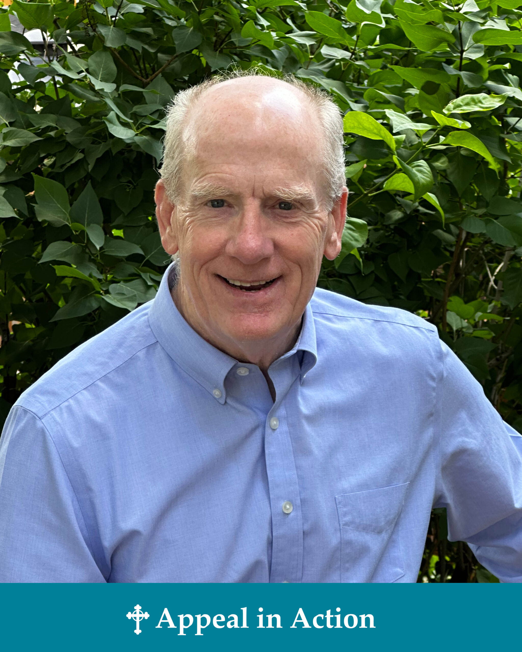 A message of an elderly man in a blue shirt smiling in front of a bush.