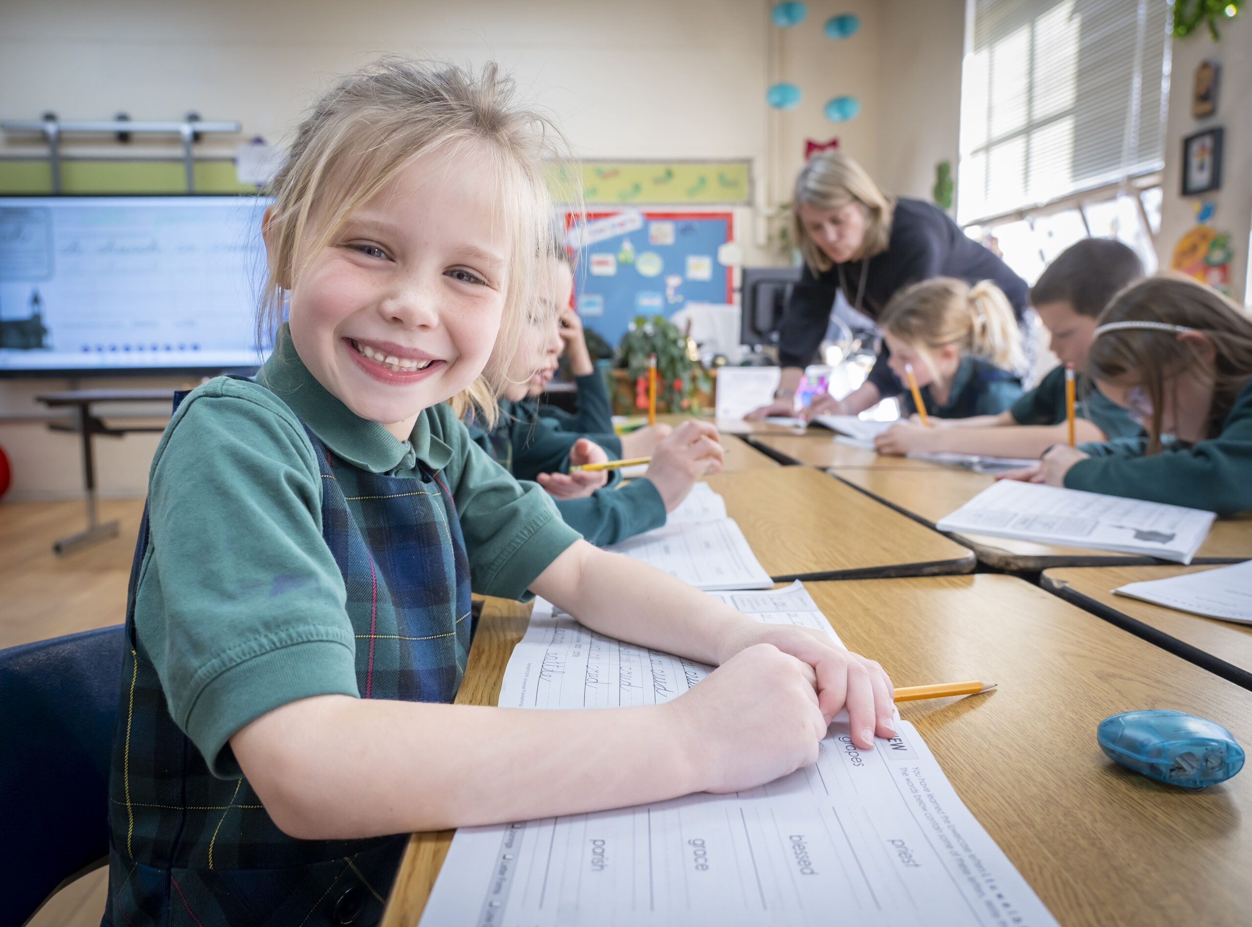 A young school girl in Denver smiling while doing an assignment.
