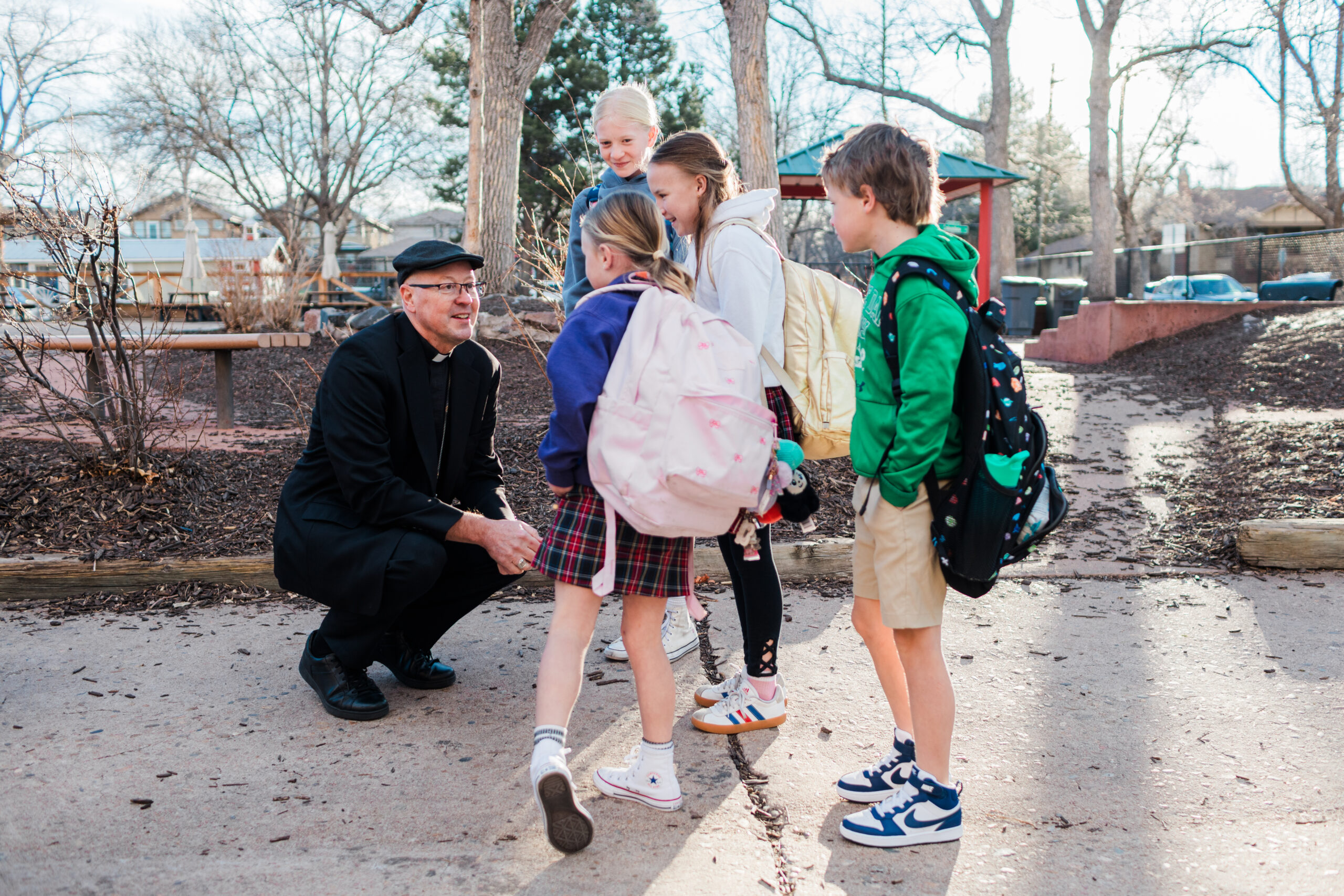 Archbishop Golka bending down to speak with a group of children outside.